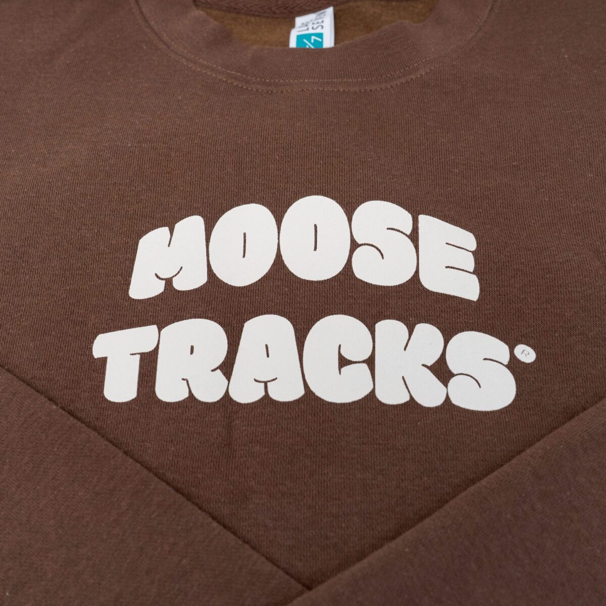 A brown crewneck sweatshirt with "Moose Tracks" in vanilla-colored screen printing