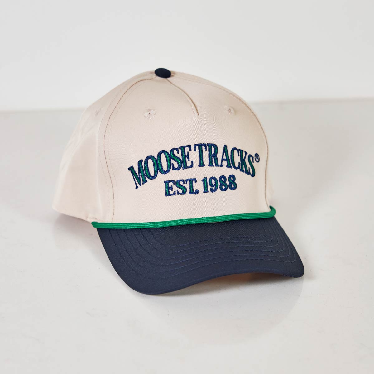 A white and blue Moose Tracks Two-Tone Rope Hat with "Moose Tracks EST. 1988" is sitting on against a white background.