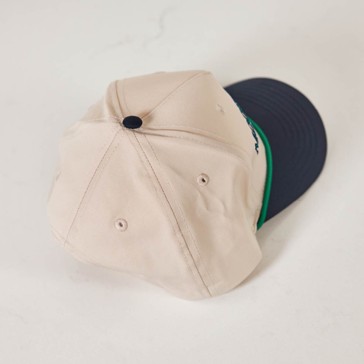 The top of a white and blue Moose Tracks Two-Two Rope Hat that is sitting backwards on against a white background.